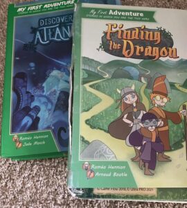 Two children's adventure books titled "Discover Atlantis" and "Finding the Dragon," featuring colorful illustrations and characters. The books are part of the "My First Adventure" series, encouraging interactive storytelling for young readers.