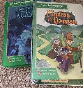 Two children's adventure books titled "Discover Atlantis" and "Finding the Dragon," featuring colorful illustrations and characters. The books are part of the "My First Adventure" series, encouraging interactive storytelling for young readers.