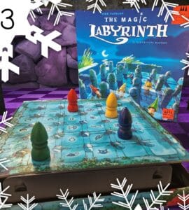 Colorful game pieces on a blue game board for "The Magic Labyrinth," a family board game by Dirk Baumann, featuring a whimsical design and hidden pathways. The game box is visible in the background, showcasing its enchanting artwork.