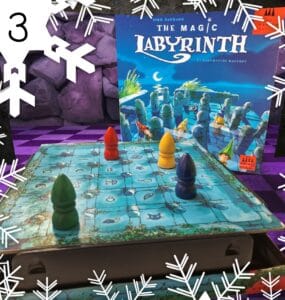 Colorful game pieces on a blue game board for "The Magic Labyrinth," a family board game by Dirk Baumann, featuring a whimsical design and hidden pathways. The game box is visible in the background, showcasing its enchanting artwork.