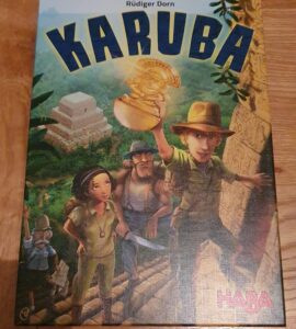 Box cover of the board game "Karuba" by Rüdiger Dorn, featuring four adventurers in an ancient jungle setting, with a temple in the background and a treasure in the foreground, published by HABA.