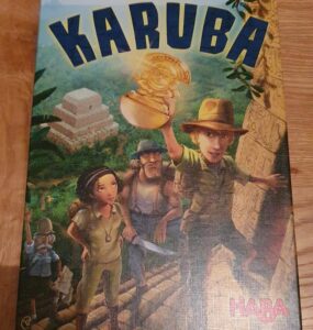 Box cover of the board game "Karuba" by Rüdiger Dorn, featuring four adventurers in an ancient jungle setting, with a temple in the background and a treasure in the foreground, published by HABA.