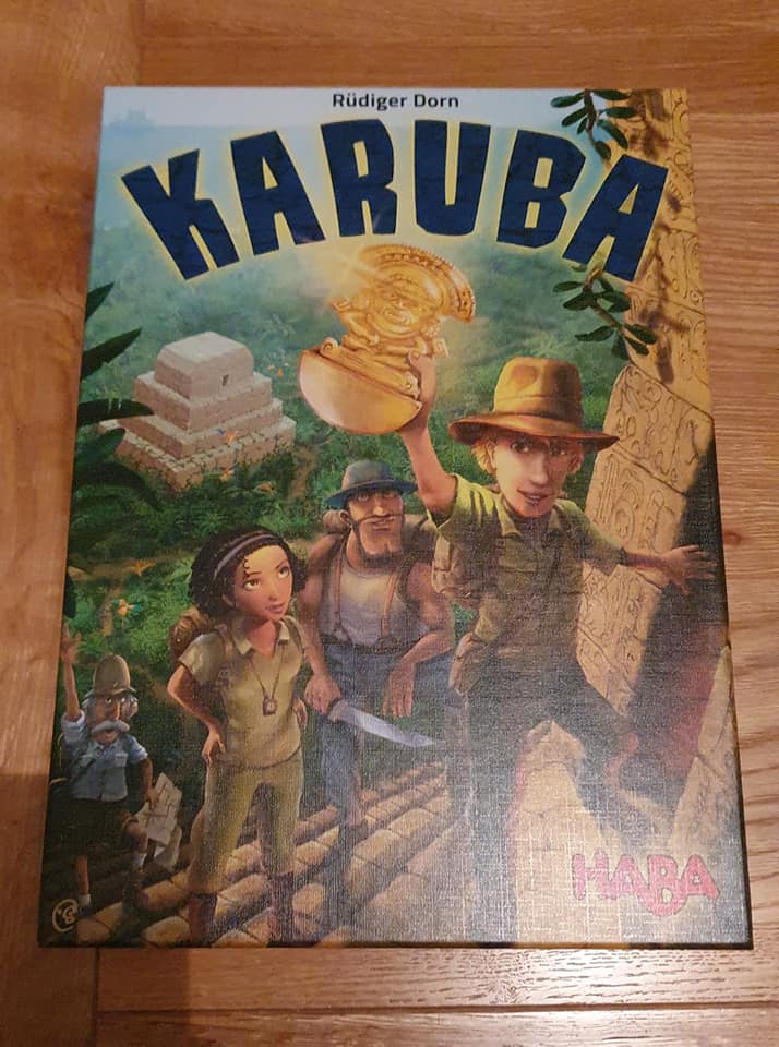 Box cover of the board game "Karuba" by Rüdiger Dorn, featuring four adventurers in an ancient jungle setting, with a temple in the background and a treasure in the foreground, published by HABA.