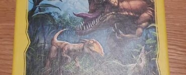 Colorful box of the board game "Dino World" featuring dinosaur illustrations, with a warning label about choking hazards. Designed by Marco Pranzo, Virginio Gigli, and Flaminia Brasini, and manufactured by HABA in Germany.