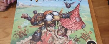 Image of the board game "Flyin' Goblin" featuring colorful artwork of a goblin in goggles flying above a medieval village, with game components visible on the box. The game is designed for 2-4 players and offers a playful theme of goblin adventures.