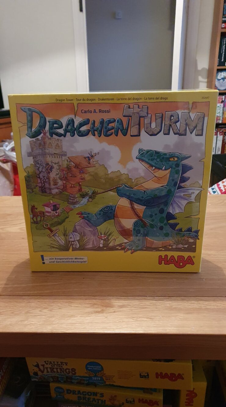 Drachen Turm board game box featuring colorful artwork of a dragon and a whimsical castle, designed by Carlo A. Rossi, published by HABA. Ideal for cooperative play and memory skills development.