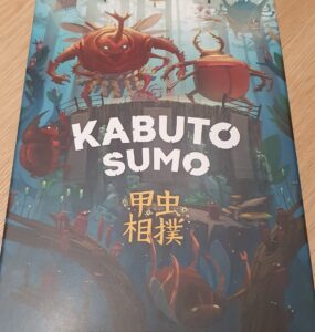 Kabuto Sumo board game box featuring colorful artwork of anthropomorphic insects engaged in a sumo wrestling match, designed by Tony Miller and illustrated by Kwanchai Moriya. The title "Kabuto Sumo" is prominently displayed at the top, with Japanese characters beneath it, set against a whimsical forest background.