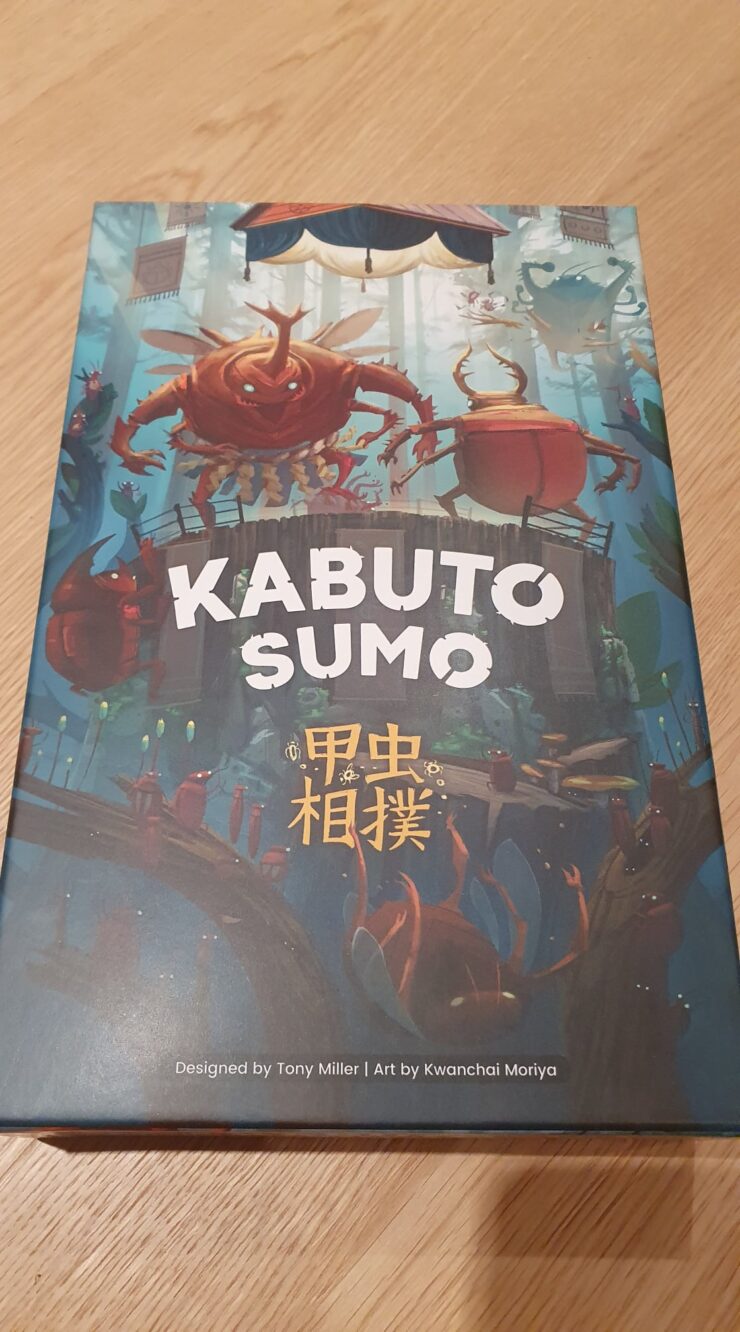 Kabuto Sumo board game box featuring colorful artwork of anthropomorphic insects engaged in a sumo wrestling match, designed by Tony Miller and illustrated by Kwanchai Moriya. The title "Kabuto Sumo" is prominently displayed at the top, with Japanese characters beneath it, set against a whimsical forest background.