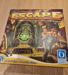 Board game "Escape: The Curse of the Temple" by Queen Games, featuring a vibrant cover illustration of an adventurer navigating a temple with a totem and treasure.