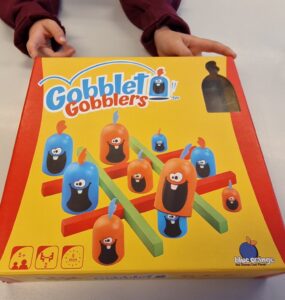 Colorful Gobblet Gobblers game box featuring playful characters and game components, designed for ages 5 and up, suitable for 2 players with a quick 5-minute playtime.