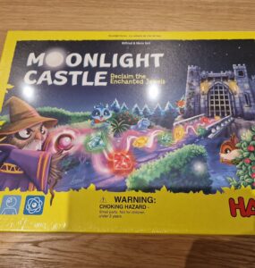 Colorful board game box for "Moonlight Castle" by HABA, featuring a whimsical wizard, enchanted jewels, and a castle backdrop. Designed for 2-4 players aged 5 and up, this game invites players to reclaim magical gems in a charming fantasy setting.