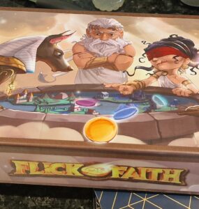 Colorful board game box for "Flick of Faith," featuring mythological characters including gods and a sphinx, with vibrant illustrations and game components displayed.