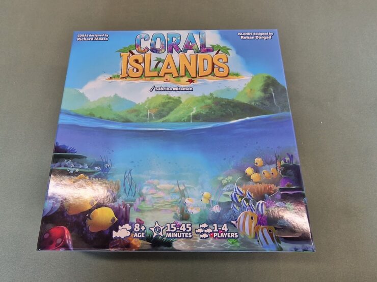 Colorful board game box for "Coral Islands," featuring vibrant underwater scenes with fish and coral. Designed by Richard Maass and Rohan Dargad, suitable for ages 8 and up, for 1-4 players, with a playtime of 15-45 minutes.