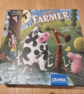 Colorful game box of "Super Farmer" featuring cartoon animals like a cow, pig, and horse, with a farmer character and playful elements, designed for 2-6 players aged 6 and up.