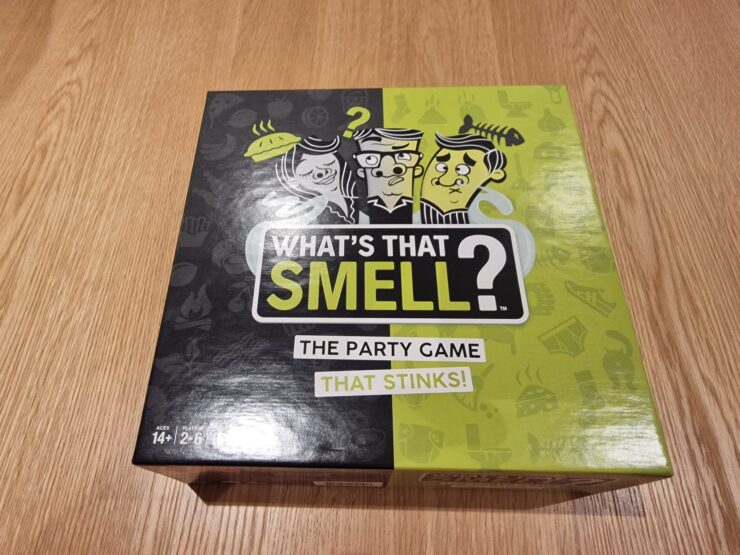 Colorful game box for "What's That Smell?" featuring humorous illustrations and the tagline "The Party Game That Stinks!" Suitable for ages 14 and up, for 2 to 6 players.