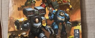 Board game box cover for "Space Marine Adventures: Rise of the Orks," featuring heroic Space Marines battling Orks. The game is designed for 1-5 players, ages 8 and up, and focuses on cooperative defense gameplay.