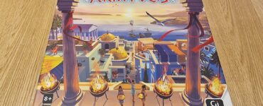 Board game Akropolis box cover featuring a vibrant illustration of an ancient city with pillars, torches, and characters, designed for 2-4 players aged 8 and up, published by Gigamic.