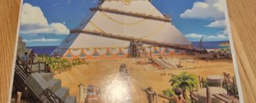 Box cover of the board game "7 Wonders: Architects" by Antoine Bauza, featuring a colorful illustration of a pyramid under construction with characters engaged in architectural activities, set against a beach backdrop. The game is produced by Repos Production.