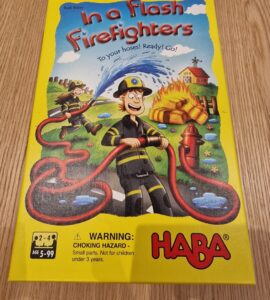 Colorful board game "In a Flash Firefighters" by HABA featuring cartoon firefighters and a fire scene, designed for ages 5 and up. The cover includes a warning about small parts for children under 3 years.