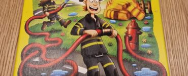 Colorful board game "In a Flash Firefighters" by HABA featuring cartoon firefighters and a fire scene, designed for ages 5 and up. The cover includes a warning about small parts for children under 3 years.
