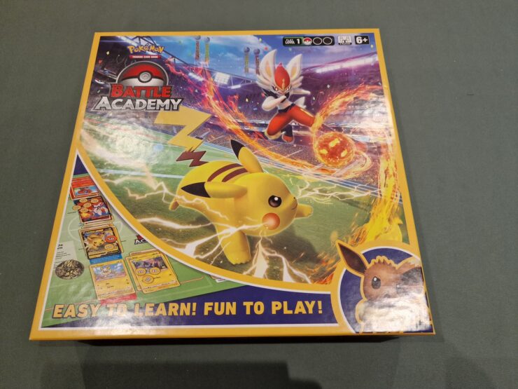 Pokemon Battle Academy board game box featuring Pikachu and an action scene with a character using a fire attack. The design highlights the game’s accessibility with the tagline "Easy to Learn! Fun to Play!" Suitable for ages 6 and up.