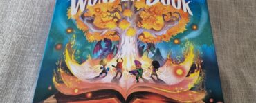 Cover of the board game "Wonder Book," featuring vibrant artwork of a magical tree, characters exploring a fantastical world, and an open book emitting colorful light effects. Ideal for family game nights and fantasy enthusiasts.