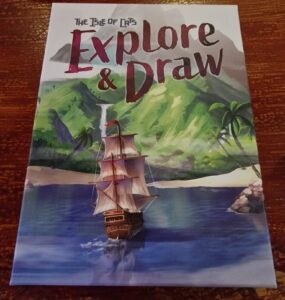 Cover of "The Isle of Cats: Explore & Draw," featuring a colorful illustration of a sailing ship navigating calm waters, surrounded by lush green mountains and tropical palm trees.