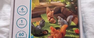 Box of the "Squirrels Go Nuts!" puzzle game by Smart Games, featuring colorful squirrel figurines and acorns on a green base. Designed for one player aged 6 and up, it includes 60 challenges ranging from easy to expert.