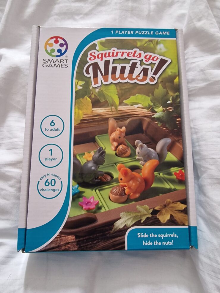 Box of the "Squirrels Go Nuts!" puzzle game by Smart Games, featuring colorful squirrel figurines and acorns on a green base. Designed for one player aged 6 and up, it includes 60 challenges ranging from easy to expert.