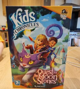 Colorful board game box titled "Kids Chronicles: Quest for the Moon Stones," featuring adventurous characters riding a magical purple cat against a whimsical background. Suitable for ages 7 and up, designed by David Cicurel, published by Lucky Duck Games.