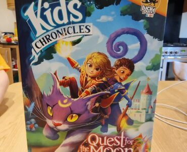 Colorful board game box titled "Kids Chronicles: Quest for the Moon Stones," featuring adventurous characters riding a magical purple cat against a whimsical background. Suitable for ages 7 and up, designed by David Cicurel, published by Lucky Duck Games.