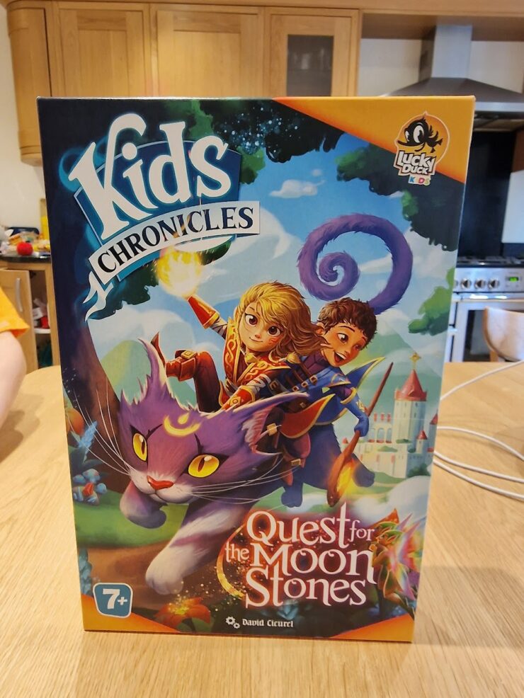 Colorful board game box titled "Kids Chronicles: Quest for the Moon Stones," featuring adventurous characters riding a magical purple cat against a whimsical background. Suitable for ages 7 and up, designed by David Cicurel, published by Lucky Duck Games.