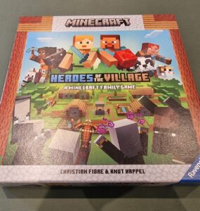 Minecraft Heroes of the Village board game box featuring colorful graphics, characters, and gameplay elements. Designed for 2-4 players aged 7 and up, created by Christian Fiore and Knut Happel, published by Ravensburger.