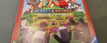 Minecraft Heroes of the Village board game box featuring colorful graphics, characters, and gameplay elements. Designed for 2-4 players aged 7 and up, created by Christian Fiore and Knut Happel, published by Ravensburger.