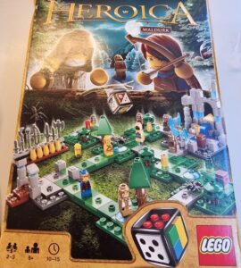 LEGO Heroica Waldurk board game box featuring a colorful game layout with miniature characters, trees, and a dice, designed for 2-3 players aged 8 and up, with an estimated playtime of 10-15 minutes.