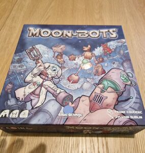 Board game "Moon-Bots" featuring colorful artwork of robots on a lunar landscape, designed for 2-4 players aged 7 and up, with an estimated playtime of 30 minutes.