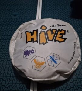 Hive board game packaging featuring the title "HIVE" and illustrations of insect tokens. The design showcases a hexagonal theme, emphasizing the game's strategic gameplay involving bugs like ants and beetles.