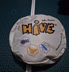 Hive board game packaging featuring the title "HIVE" and illustrations of insect tokens. The design showcases a hexagonal theme, emphasizing the game's strategic gameplay involving bugs like ants and beetles.