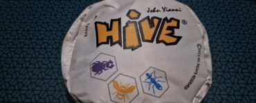 Hive board game packaging featuring the title "HIVE" and illustrations of insect tokens. The design showcases a hexagonal theme, emphasizing the game's strategic gameplay involving bugs like ants and beetles.