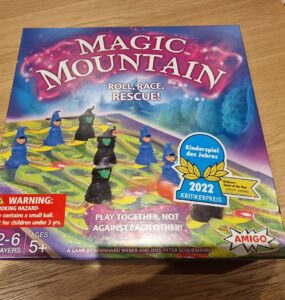 Colorful board game box for "Magic Mountain," featuring playful wizard figures and a vibrant game board. Highlights include "Roll, Race, Rescue!" tagline, age recommendation of 5+, and a warning about small parts. Recognized with the 2022 Children's Game of the Year Critics Award, suitable for 2-6 players.