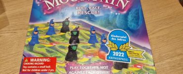 Colorful board game box for "Magic Mountain," featuring playful wizard figures and a vibrant game board. Highlights include "Roll, Race, Rescue!" tagline, age recommendation of 5+, and a warning about small parts. Recognized with the 2022 Children's Game of the Year Critics Award, suitable for 2-6 players.