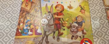 Colorful board game box for "Quacks & Co. Quedlinburg Dash!" by Wolfgang Warsch, featuring cheerful characters, a donkey, and festive decorations. The game is published by Schmidt.