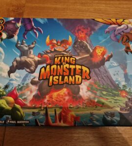 Box cover of the board game "King of Monster Island" featuring colorful artwork of giant monsters, a volcano, and a coastal landscape. Designed by Richard Garfield and Paul Mafavon, suitable for 2-5 players aged 10 and up, with a playtime of 45-60 minutes.