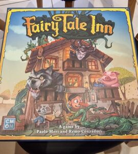 Colorful board game box for "Fairy Tale Inn" featuring whimsical characters like a wolf, a pig, and a wooden puppet, designed by Paolo Mori and Remo Conzadori. The illustration showcases a charming inn surrounded by fairy tale elements.