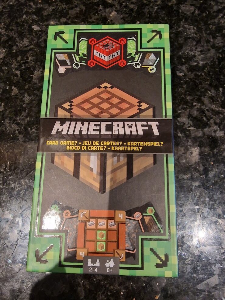 Minecraft card game packaging featuring a TNT block, crafting table, and player instructions. Suitable for 2-4 players aged 8 and up.
