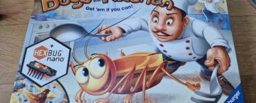 Colorful board game box for "Bugs in the Kitchen" featuring a chef and a cartoon bug, highlighting the HEXBUG nano component. Suitable for ages 6 and up, it combines fun and strategy in a kitchen-themed setting.