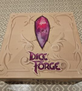 Dice Forge board game box featuring a prominent purple gem design, created by Régis Bonnessée, displayed on a patterned table surface.
