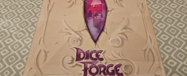 Dice Forge board game box featuring a prominent purple gem design, created by Régis Bonnessée, displayed on a patterned table surface.