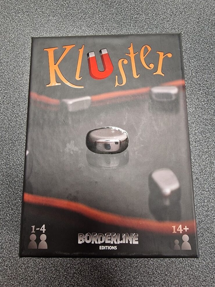 Box of the game "KluSter" by Borderline Editions, featuring a metallic game piece on a dark background, suitable for 1-4 players aged 14 and up.
