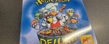 Board game box for "Heckmeck Deluxe" by Reiner Knizia, featuring cartoonish chickens and a chef grilling skewers, with vibrant colors and a playful design. Ideal for family game nights and gatherings.